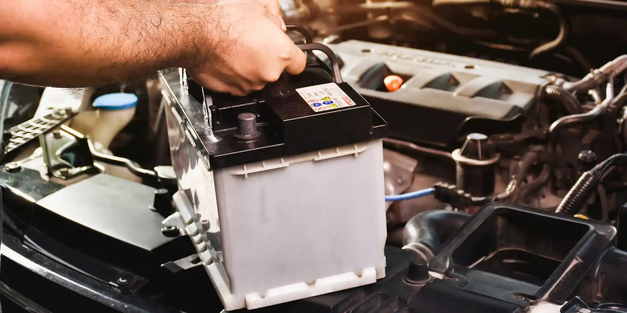 A auto mechanic carries a replacement car battery for car electr A auto mechanic carries a replacement car battery for car